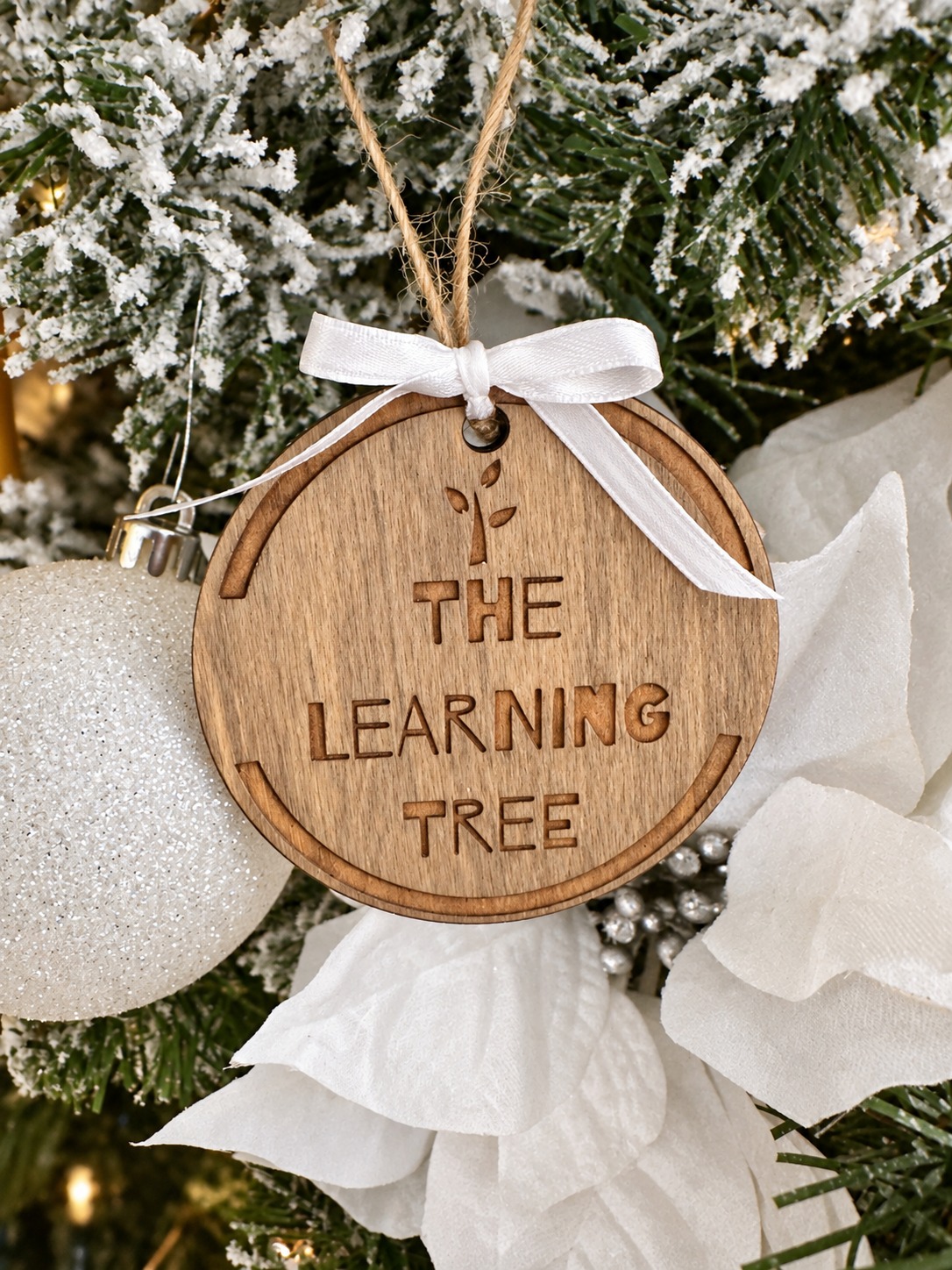 Wooden Learning Tree logo ornament with white ribbon