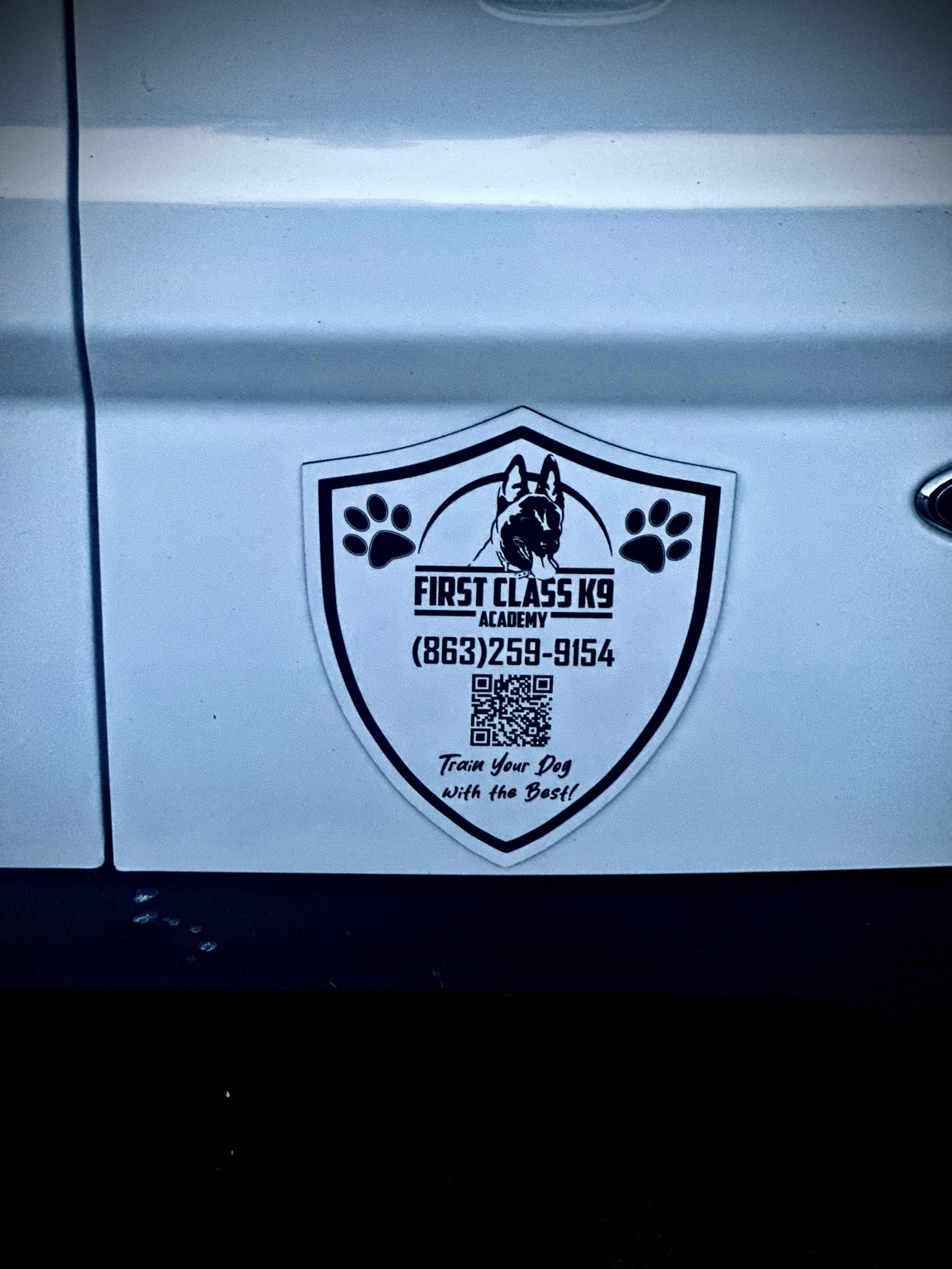 Custom shield-shaped First Class K9 Academy magnetic business sign installed on a vehicle