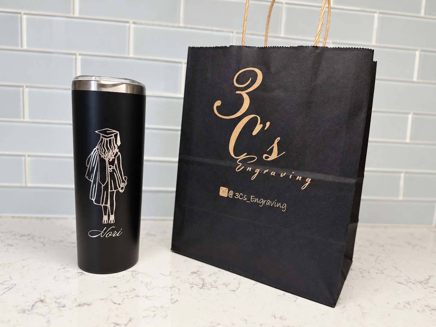 Black graduation tumbler engraved Nori beside a 3Cs Engraving gift bag