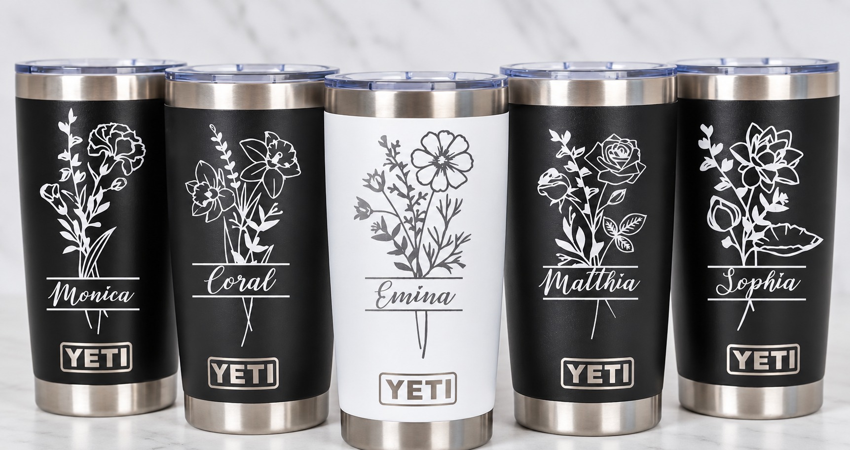 Five black and white tumblers engraved with floral designs and personalized names
