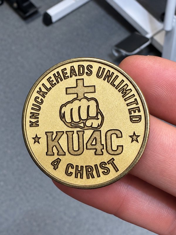 Custom brass KU4C challenge coin with cross and fist artwork