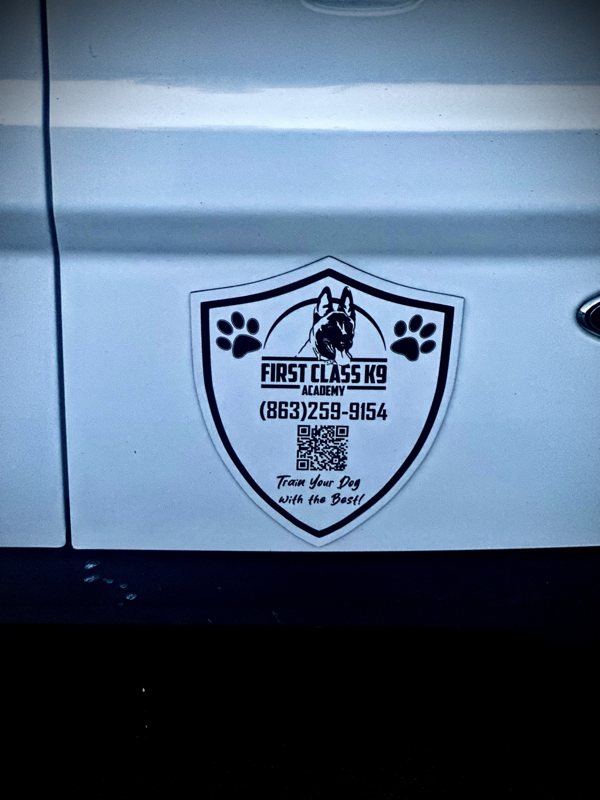 Custom shield-shaped First Class K9 Academy magnetic business sign installed on a vehicle