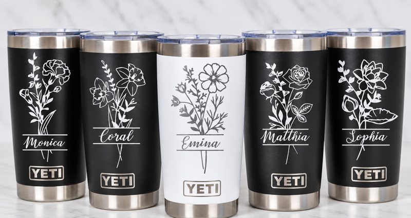 Five black and white tumblers engraved with floral designs and personalized names