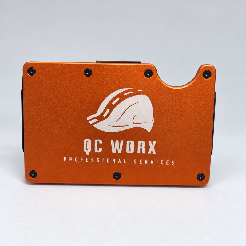 Orange metal wallet engraved with the QC WORX business logo