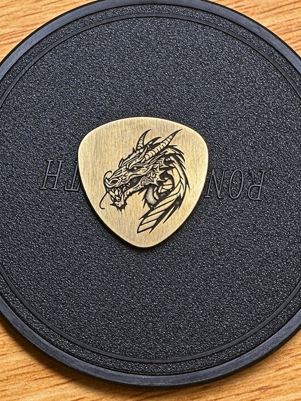 Brass guitar pick with a custom dragon engraving